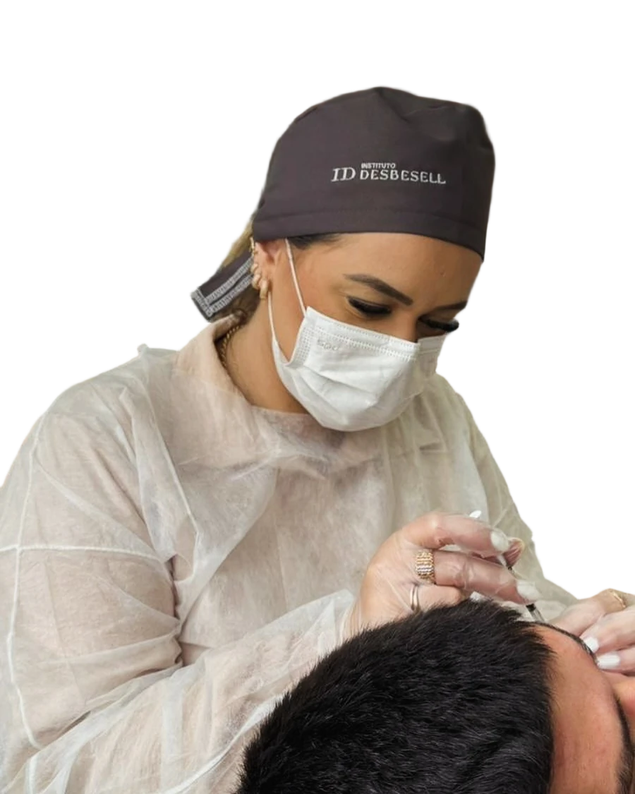 Dra. Ivana Bordignon de touca, máscara e luvas, com uma seringa na mão, realizando um procedimento na região da testa de um paciente.